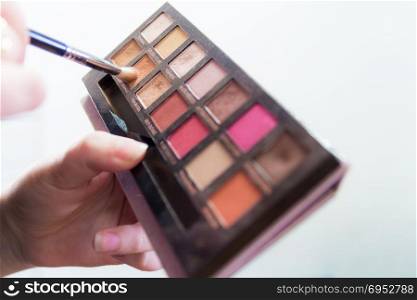 Close up of woman hands holding colorful makeup eye shadow palette.