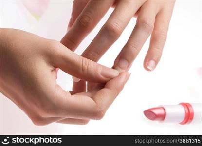 close up of woman hands with a red lipstick and pink petals of roses all around