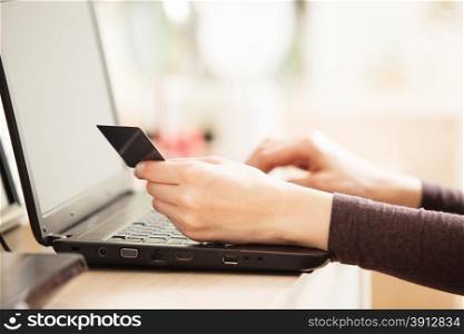 Close-up of woman holding credit card and using laptop