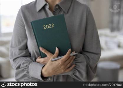 Close Up Of Woman Holding New Year 2022 Diary At Home
