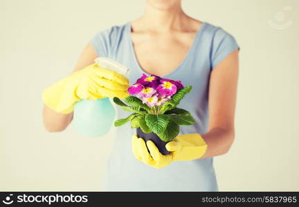 close up of woman holding pot with flower and spray bottle