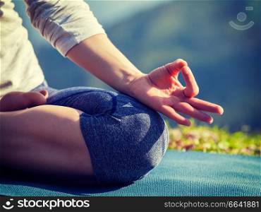 Close up of woman in Padmasana yoga lotus pose with chin mudra outdoors with copyspace. Vintage retro effect filtered hipster style image.. Close up Padmasana lotus pose