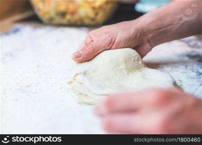 Close up of woman kneading traditional dough in the kitchen