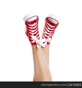 Close up of woman legs wearing a pair of red sneakers, isolated on white