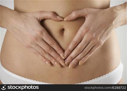 Close-Up Of Woman Making Heart Shape With Hands On Stomach
