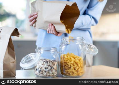 Close Up Of Woman Pouring Pasta From Plastic Free Packaging Paper Bag Into Storage Jar