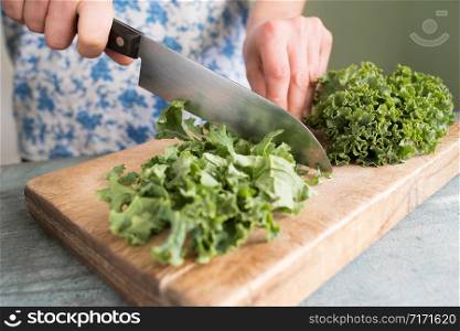 Close Up Of Woman Preparing Kale On Chopping Board