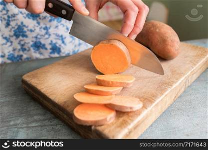 Close Up Of Woman Preparing Sweet Potato On Chopping Board