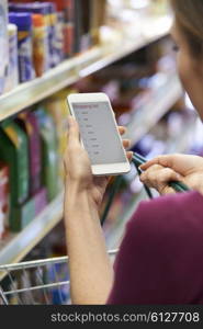 Close Up Of Woman Reading Shopping List From Mobile Phone