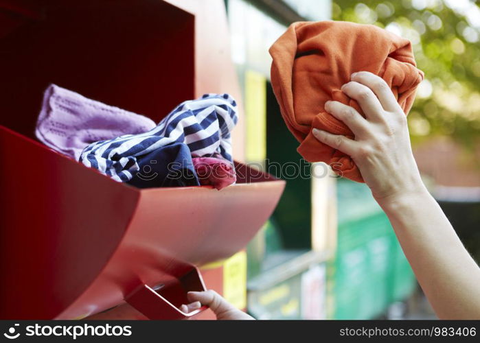 Close Up Of Woman Recycling Clothing At Clothes Bank