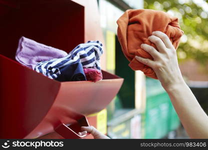 Close Up Of Woman Recycling Clothing At Clothes Bank
