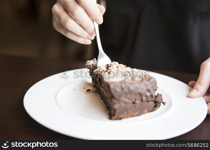 Close-up of woman&rsquo;s hand cutting chocolate pastry