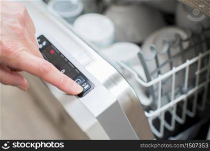 Close Up Of Woman&rsquo;s Hand Pressing Start Button On Dishwasher