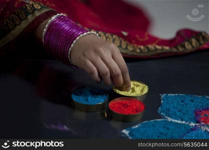 Close-up of woman&rsquo;s hand with bangles making rangoli