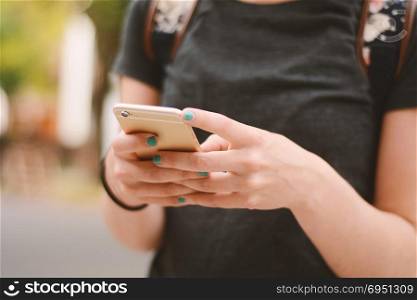 Close up of woman&rsquo;s hands texting with smartphone. Technology concept. Outdoors