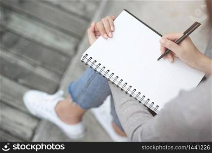 Close up of woman's hands writing in spiral notepad placed