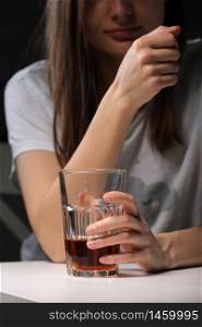 Close up of woman sitting and holds glass with whiskey or cognac having alcohol addiction, depressed female drinking strong alcohol suffering from personal relationships problems.. Close up of woman sitting and holds glass with whiskey or cognac having alcohol addiction, depressed female drinking strong alcohol suffering from personal relationships problems