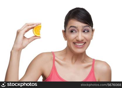 Close-up of woman squeezing orange slice while making face