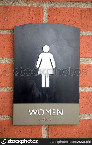 Close up of woman symbol, text and braille on a public restroom sign