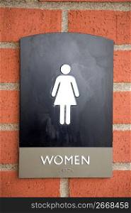 Close up of woman symbol, text and braille on a public restroom sign