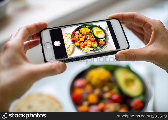 Close Up Of Woman Taking Photo Of Vegan Meal On Mobile Phone