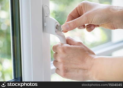 Close Up Of Woman Turning Key In Window Lock