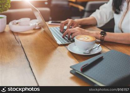 Close up of woman typing keyboard on laptop in coffee shop. People and technology concept. Freelance and Lifestyle theme. Entrepreneur and working outside office theme.