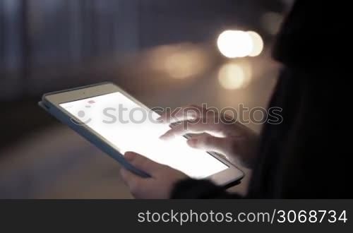 Close-up of woman using touchpad in the underground, only hands to be seen. Defocused coming train in the background