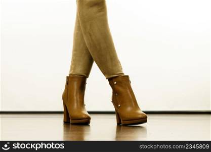 Close up of woman wearing brown suede slim fit trousers and high heels autumnal boots shoes.. Woman wearing suede leggings and high heels