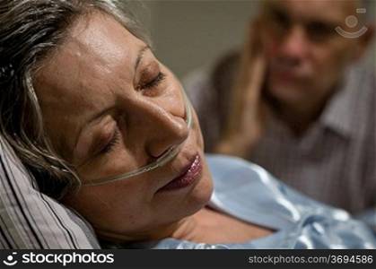 Close up of woman with nasal cannula and worried husband