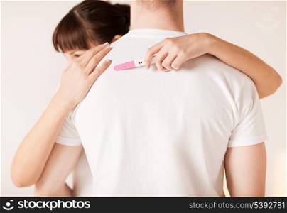 close up of woman with pregnancy test hugging man
