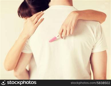 close up of woman with pregnancy test hugging man