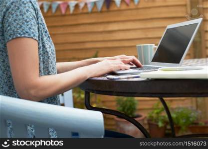 Close Up Of Woman Working From Home On Laptop Outdoors In Garden During Lockdown