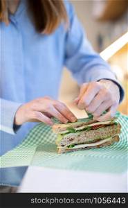 Close Up Of Woman Wrapping Sandwich In Reusable Environmentally Friendly Beeswax Wrap