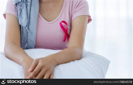 Close up of women disease mammary cancer patient with pink ribbon wearing headscarf After treatment to chemotherapy sit on bed In the bedroom at the house,healthcare,medicine concept
