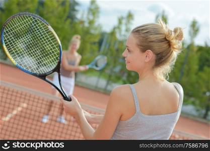 close up of women playing tennis outdoors