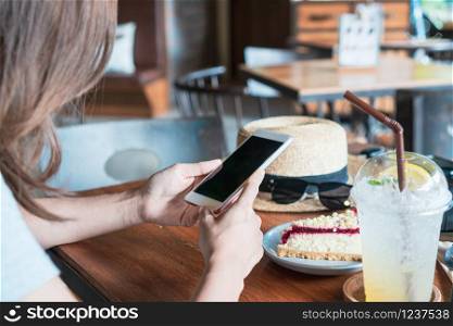 Close up of women&rsquo;s hands holding mobile phone in cafe.