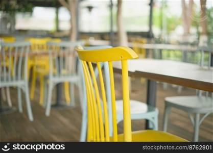 Close-up of wooden chairs in a bar. Selective focus on a yellow chair close up. Bar view, focus blur, bar decoration idea or photo for interior