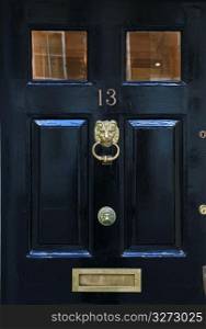 Close up of wooden door with old-fashioned, brass knocker and letter slot