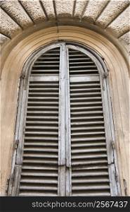 Close-up of wooden shutters and arched window in Rome, Italy.