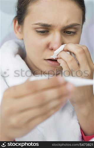 Close-up of worried woman taking her temperature