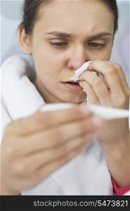 Close-up of worried woman taking her temperature