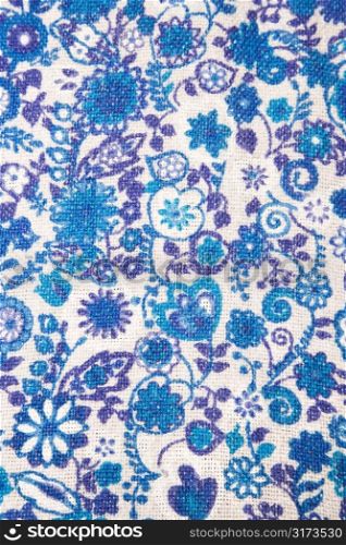 Close-up of woven vintage fabric with blue flowers and designs printed on cotton.