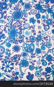 Close-up of woven vintage fabric with blue flowers and designs printed on cotton.