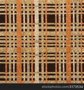 Close-up of woven vintage fabric with brown and gold crossbar pattern.