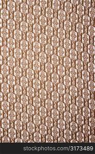 Close-up of woven vintage fabric with brown repetitive designs.