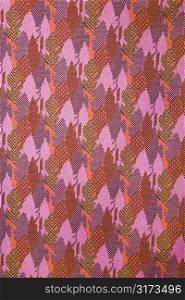 Close-up of woven vintage fabric with purple and pink repetitive designs.