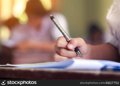 Close-up of writing hands of uniform students to test at school.