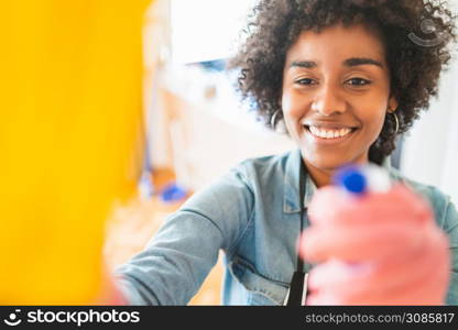 Close up of young afro woman cleaning at new home. Housekeeping and cleaning concept.