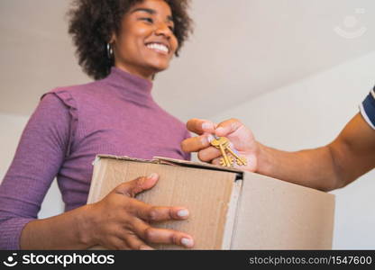 Close up of young afro woman reciving a package at home. Delivery, shipping and postal service concept.